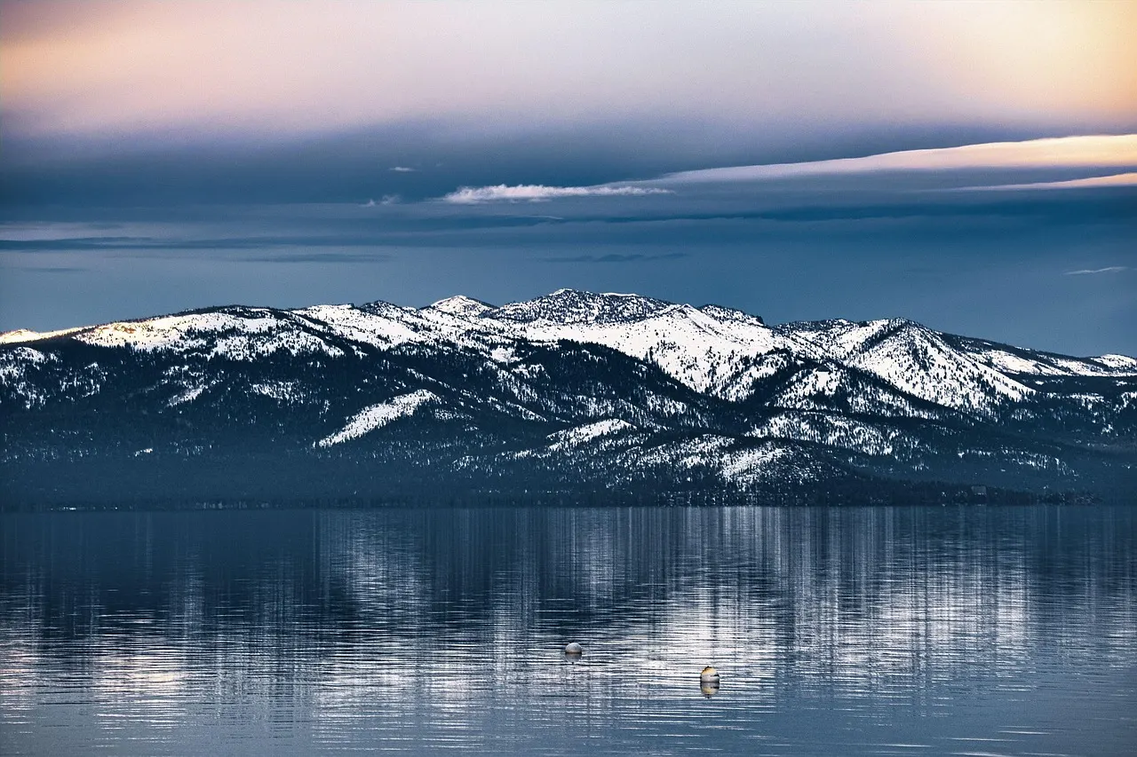 Snow-covered Sierra Nevada peaks reflected in the still water of Lake Tahoe at dusk